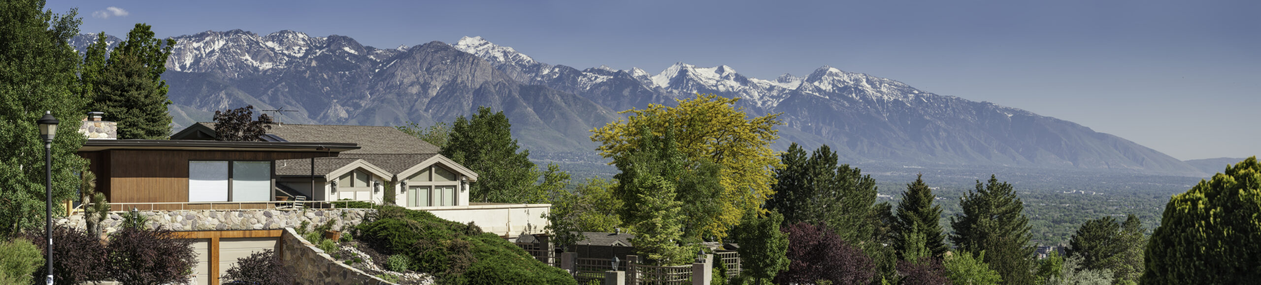 Luxury suburban homes on a tree lined street overlooked by snow capped mountains and clear blue skies. ProPhoto RGB profile for maximum color fidelity and gamut.